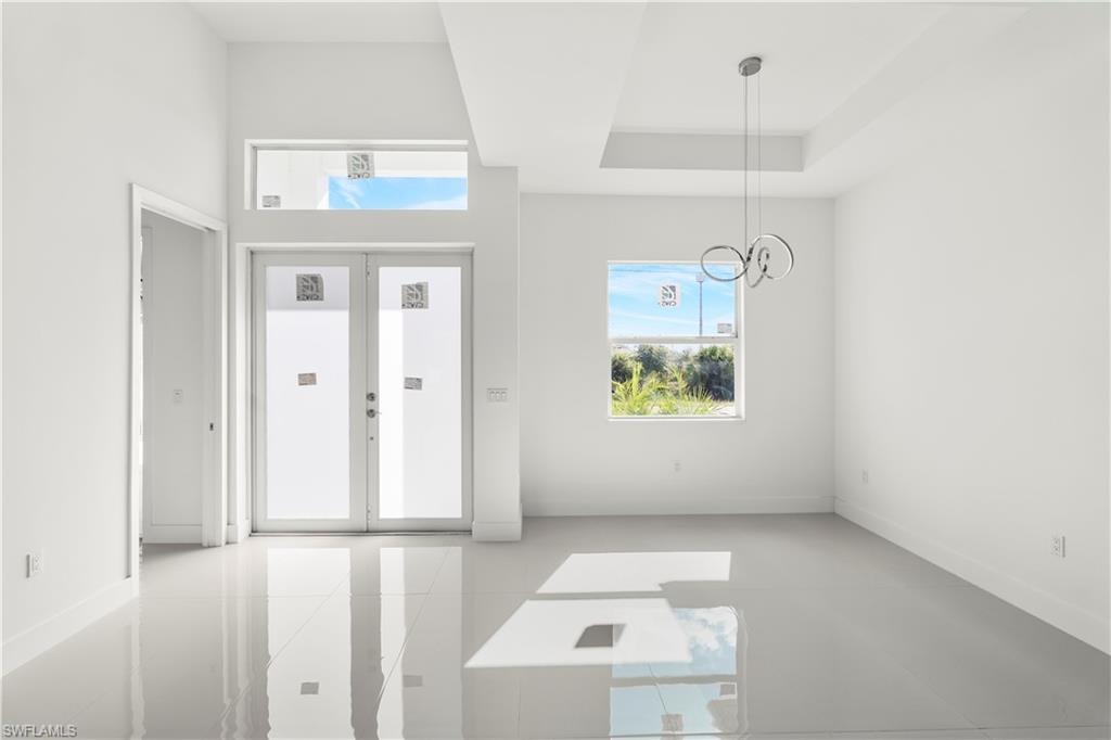 Foyer entrance featuring french doors, a chandelier, and a raised ceiling