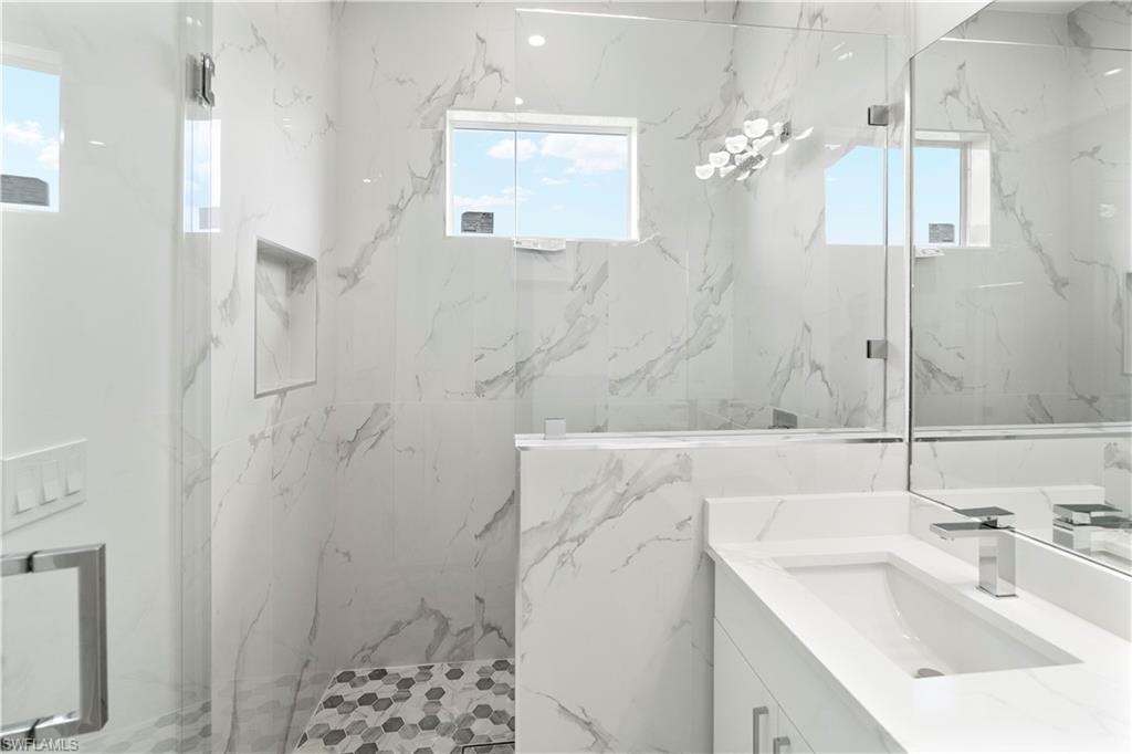Bathroom featuring vanity, plenty of natural light, and a marble finish shower