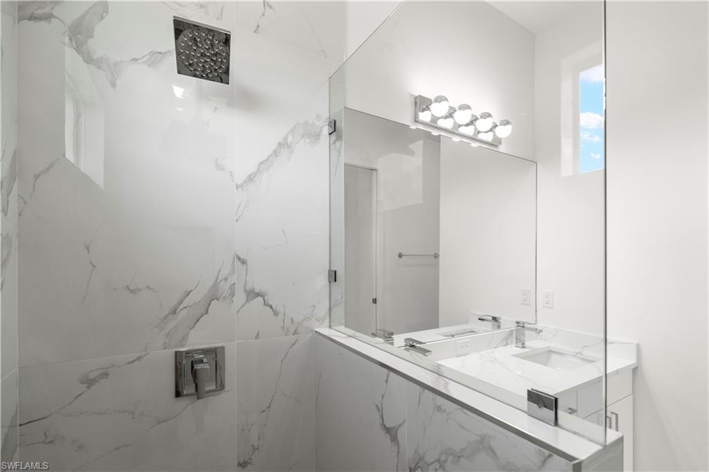 Bathroom featuring vanity and a marble finish shower