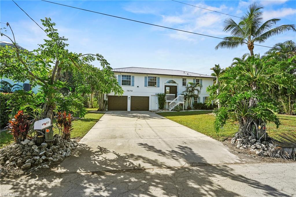 Bi-level home with a front lawn, concrete driveway, an attached garage, stairs, and a metal roof
