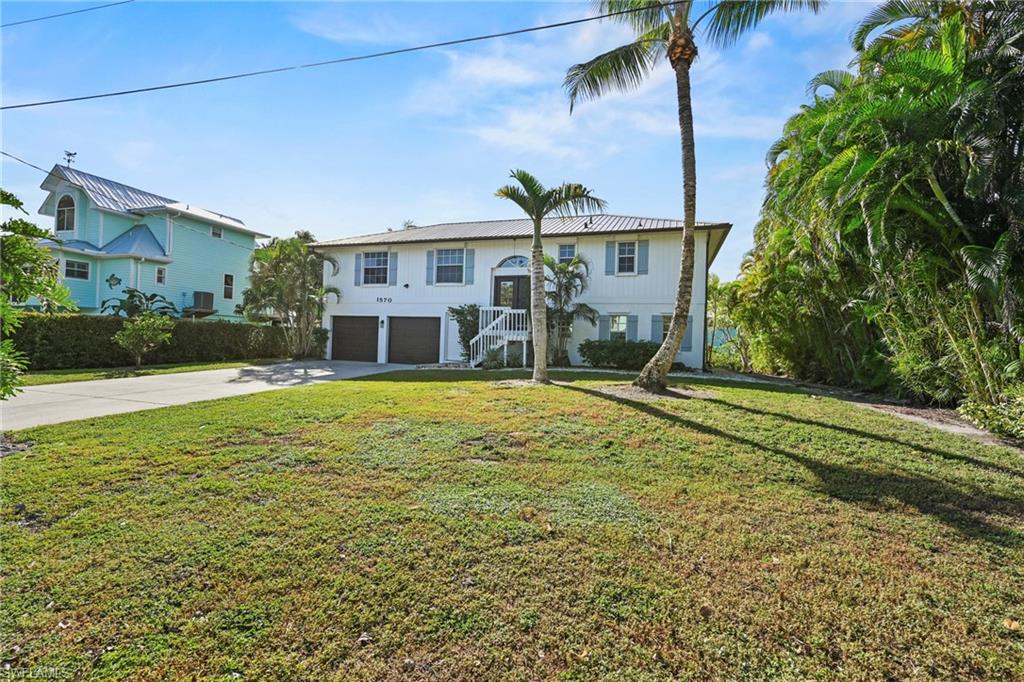 View of front of property featuring concrete driveway, a front yard, a garage, and stairway