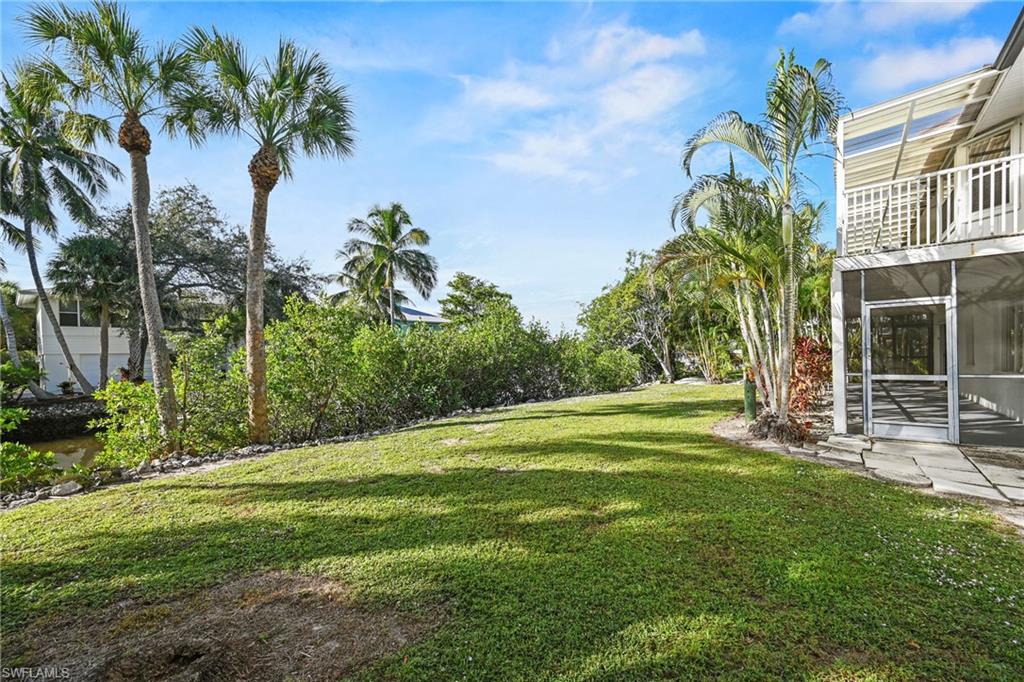 View of grassy yard featuring a sunroom and a balcony