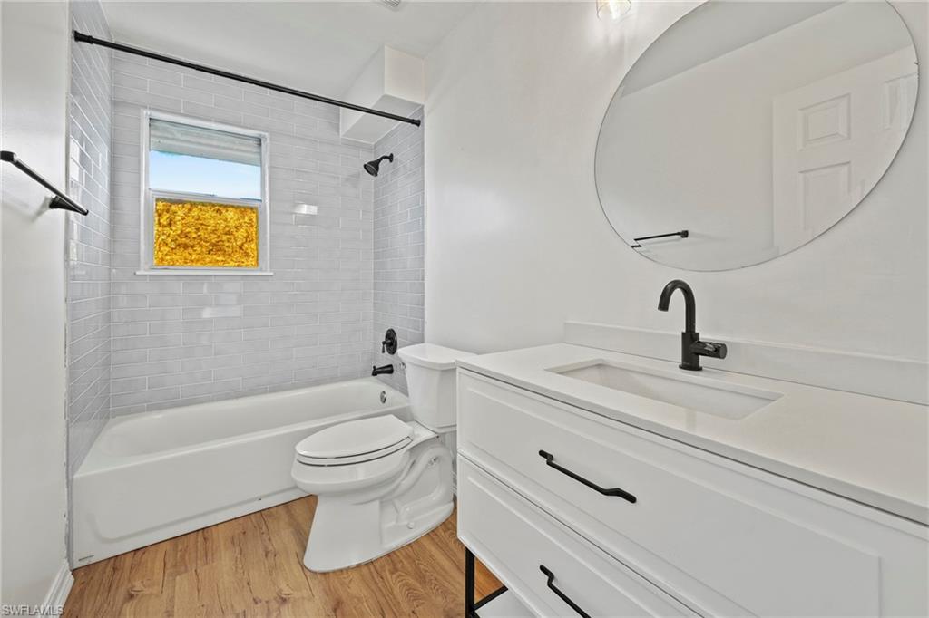 Full bath featuring vanity, light wood-type flooring, and shower / tub combination