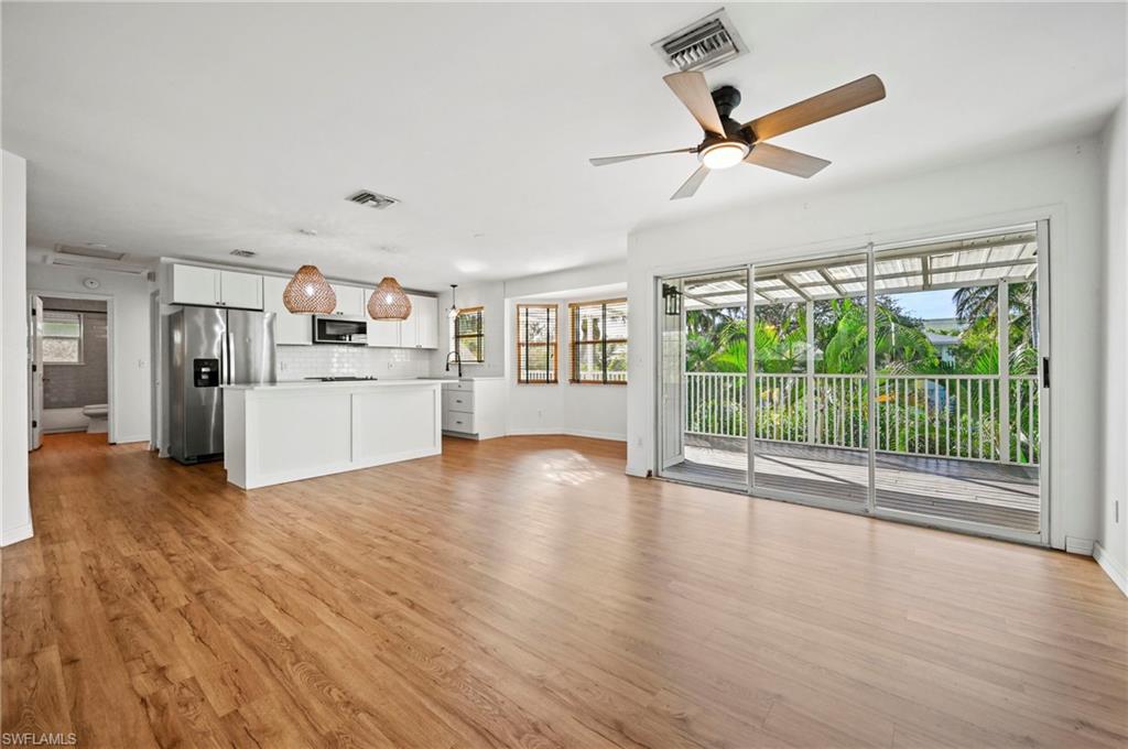 Unfurnished living room with healthy amount of natural light, a ceiling fan, and light wood-style floors