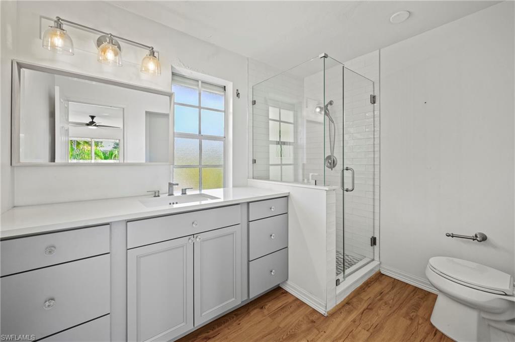 Bathroom featuring vanity, light wood-style flooring, a shower stall, and ceiling fan