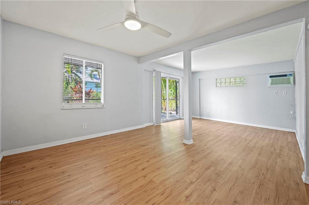 Empty room with light wood finished floors, healthy amount of natural light, a ceiling fan, and an AC wall unit