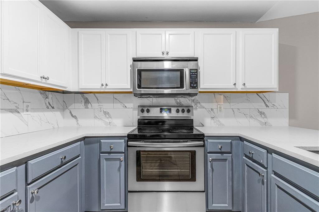 Kitchen with appliances with stainless steel finishes, backsplash, and light stone countertops