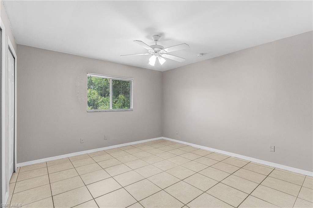 Empty room with light tile patterned flooring and ceiling fan