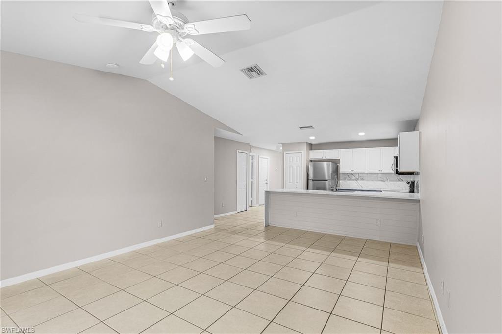 Unfurnished living room with light tile patterned floors, ceiling fan, vaulted ceiling, and recessed lighting