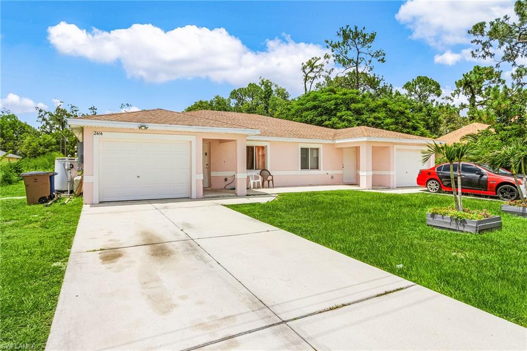 Ranch-style home featuring a front yard, driveway, stucco siding, and a garage