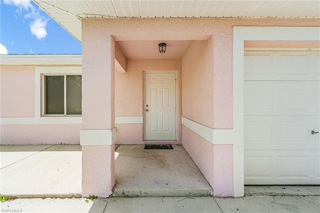Doorway to property with stucco siding, covered porch, and a garage