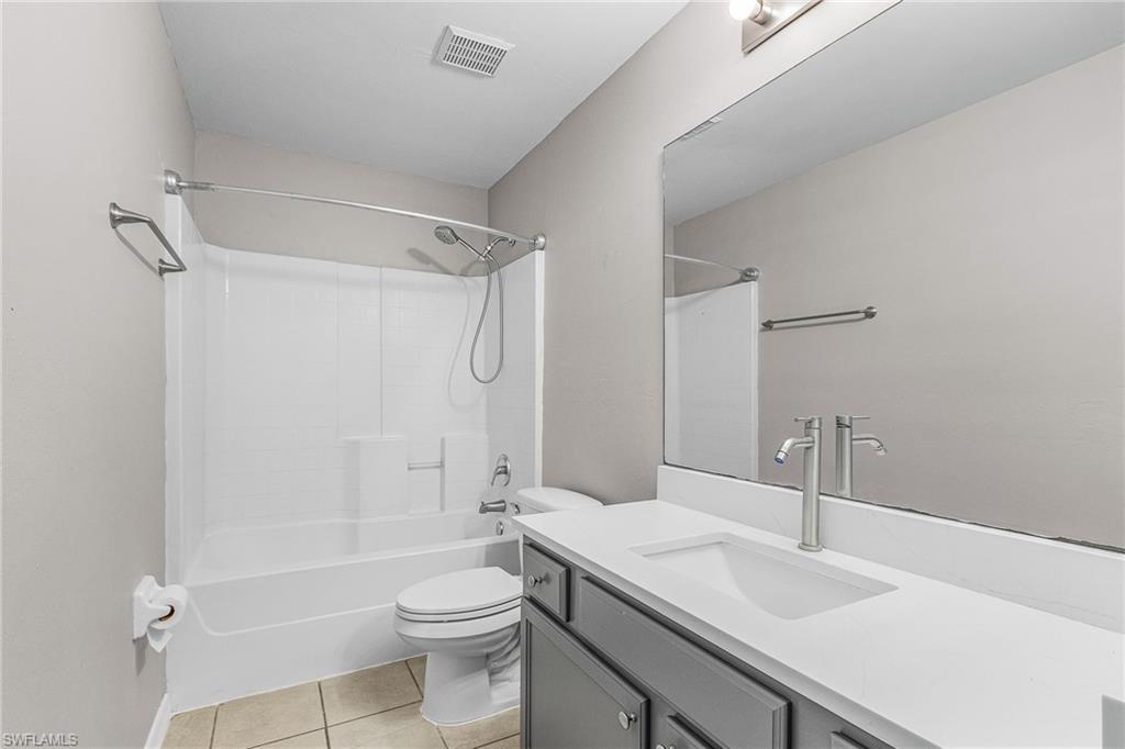 Full bath with vanity, light tile patterned flooring, and bathtub / shower combination