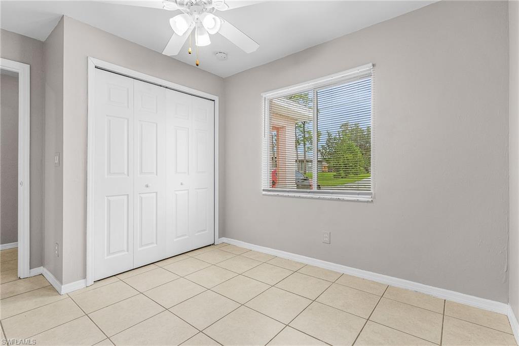 Unfurnished bedroom with light tile patterned floors, a closet, and a ceiling fan