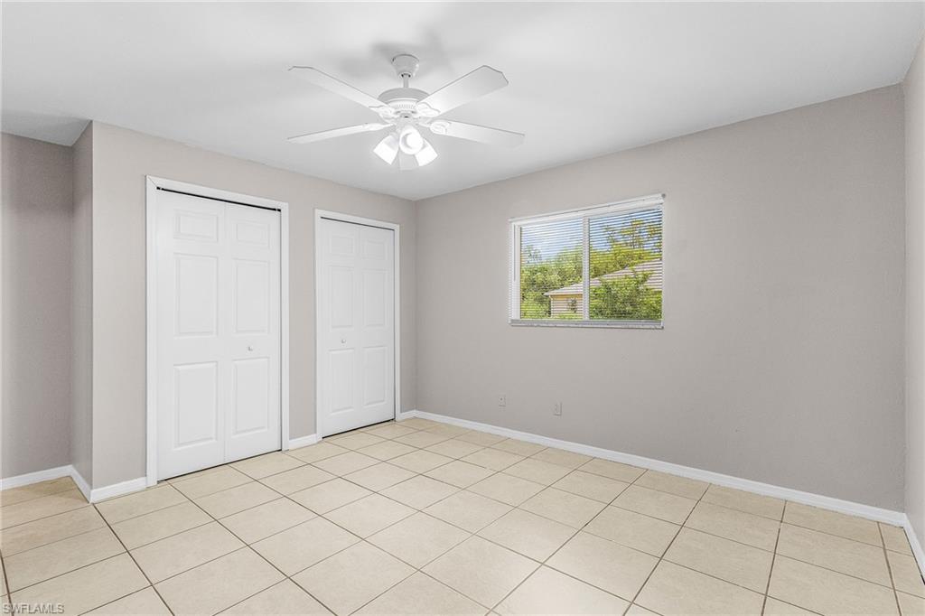 Unfurnished bedroom featuring light tile patterned floors, two closets, and ceiling fan