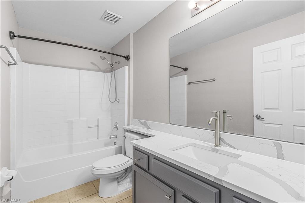 Bathroom featuring light tile patterned floors, vanity, and washtub / shower combination