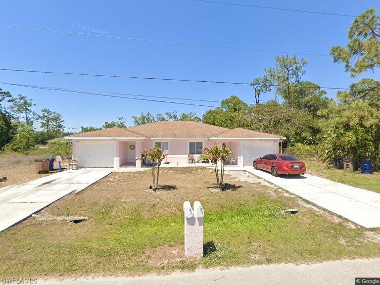 Ranch-style house featuring concrete driveway, a garage, and a front lawn