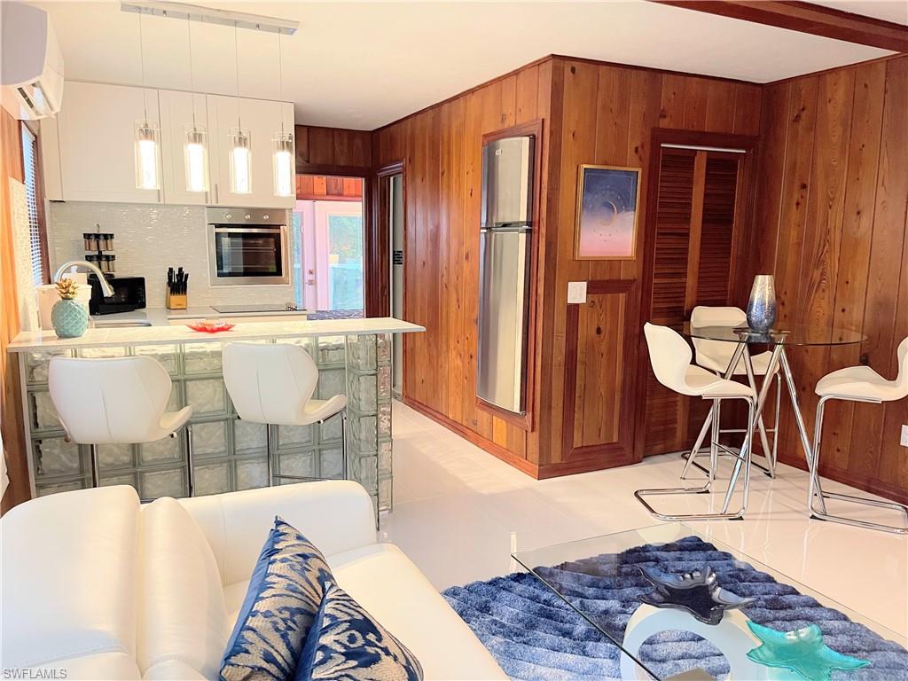 Kitchen with a kitchen breakfast bar, pendant lighting, a peninsula, appliances with stainless steel finishes, and an AC wall unit