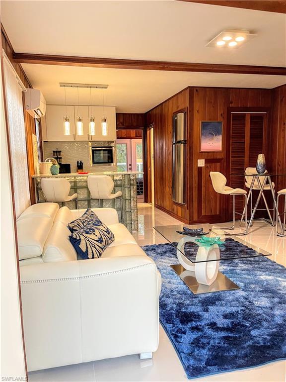 Living room with light tile patterned floors, wooden walls, and a wall mounted AC
