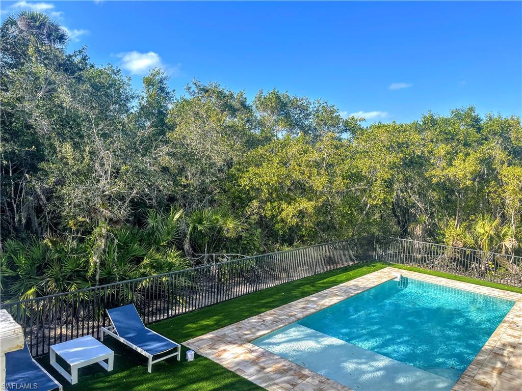 View of swimming pool featuring a fenced backyard, a patio area, and a view of trees