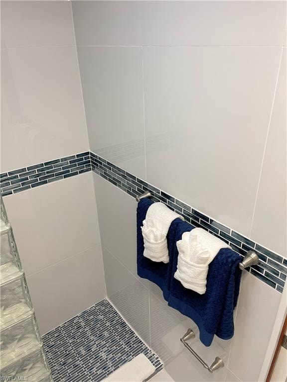 Full bath featuring tiled shower, tile walls, and tile patterned flooring