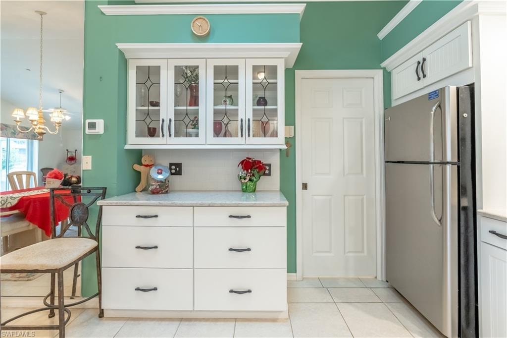 Kitchen with soft close cabinets, freestanding refrigerator, glass insert cabinets, and decorative light fixtures