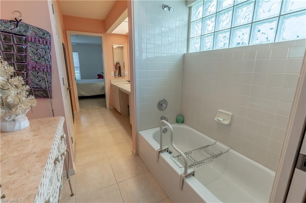 Full bath with ensuite bathroom, vanity, light tile patterned floors, and bathing tub and separate walk in shower