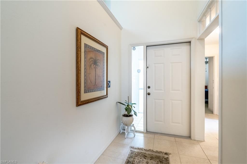 Foyer with light tile patterned flooring and baseboards