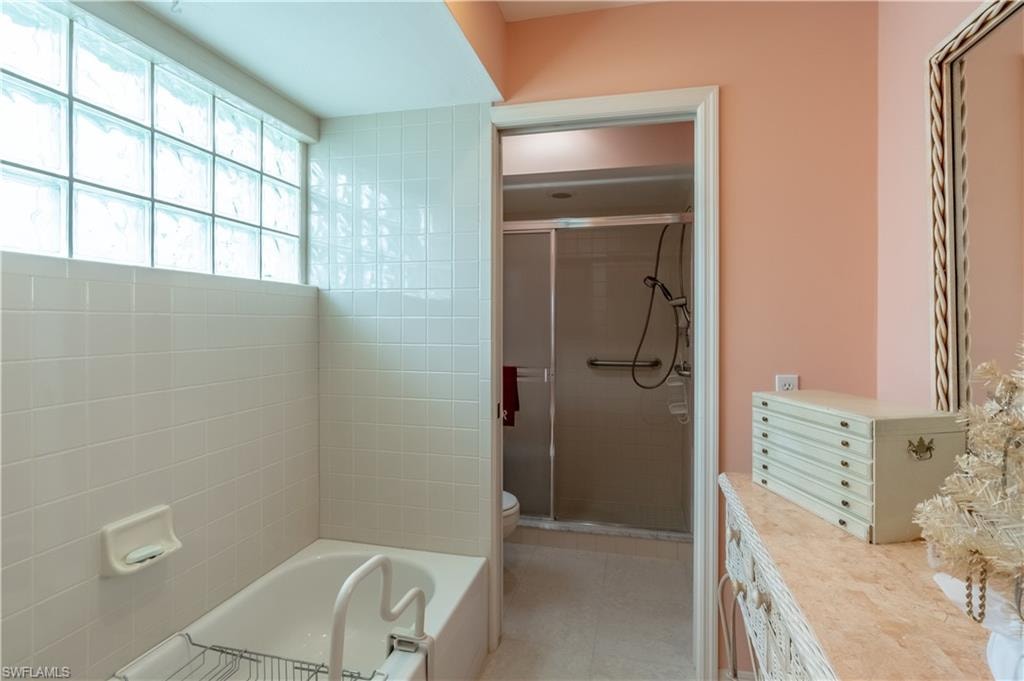 Main bathroom featuring a shower stall, a garden tub, and light tile patterned floors