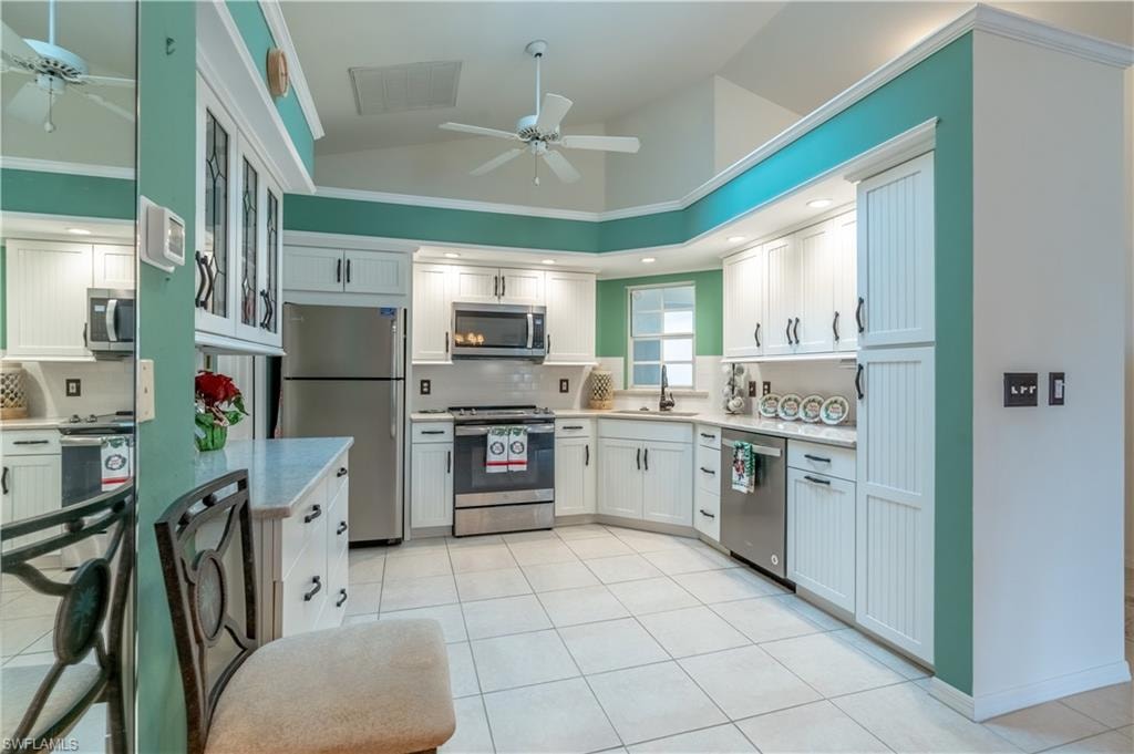 Kitchen featuring quartz countertops, a ceiling fan, vaulted ceiling, soft close cabinets and drawers with a deep granite sink