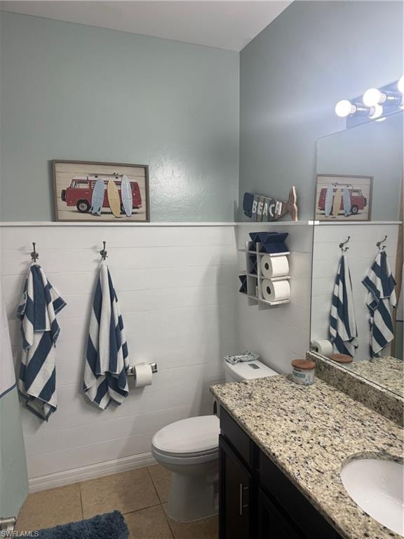 Bathroom featuring light tile patterned flooring, vanity, a wainscoted wall, and tile walls