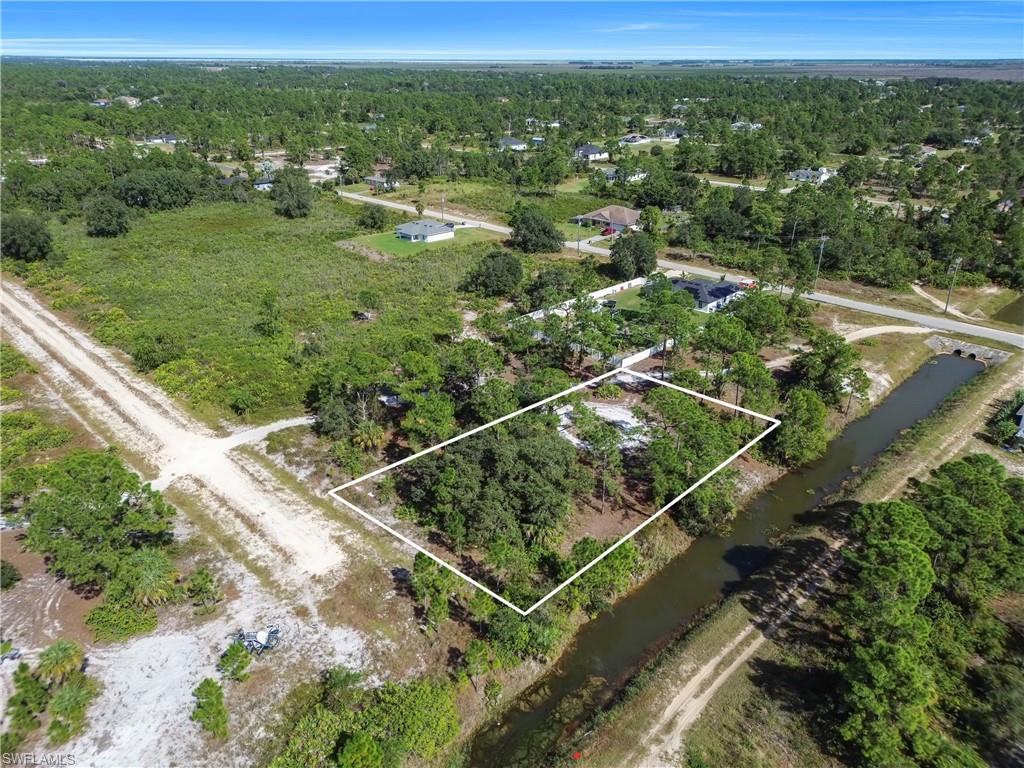 Aerial view of property and surrounding area with a nearby body of water and property parcel outlined