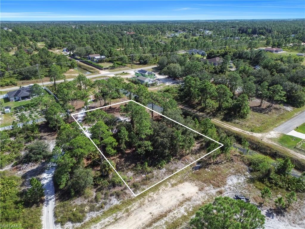 Aerial view of property's location with property parcel outlined and a heavily wooded area