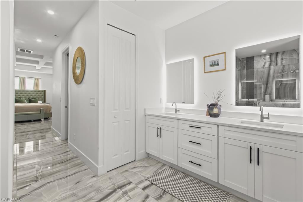Bathroom with a closet, recessed lighting, double vanity, light marble finish floors, and a marble finish shower