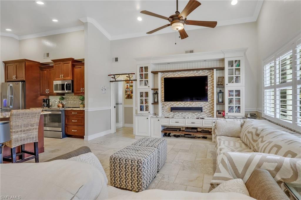 Living area with a barn door, ceiling fan, crown molding, recessed lighting, and a high ceiling
