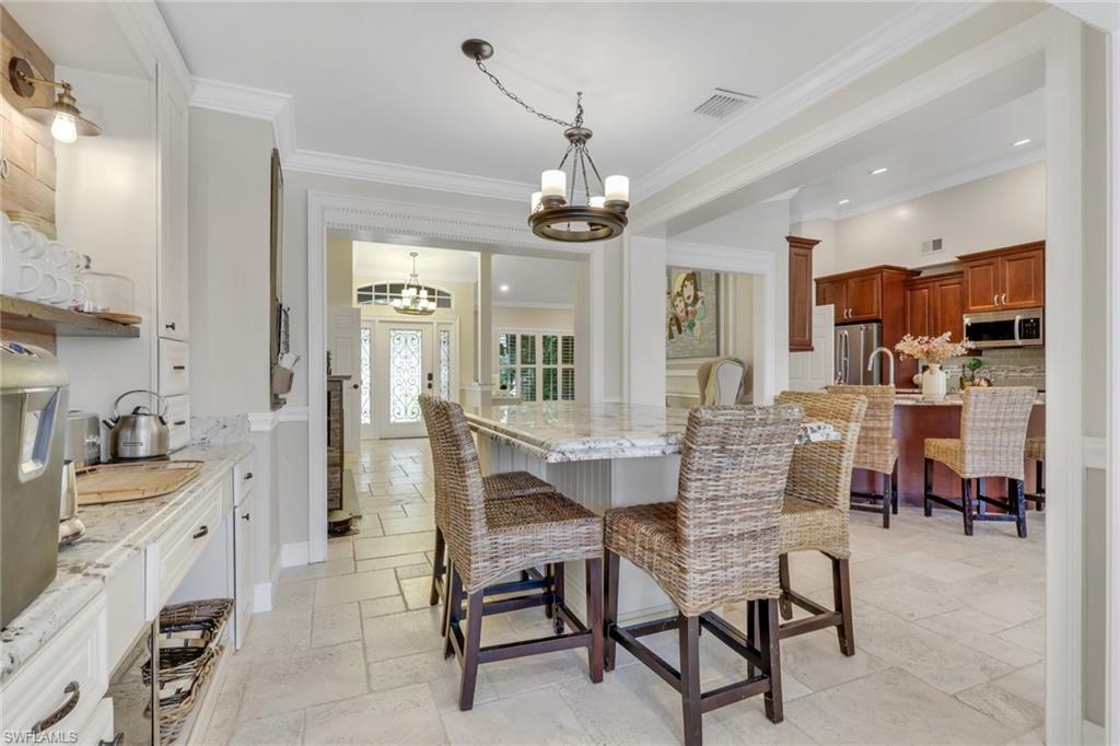 Dining space featuring stone tile flooring, a chandelier, and crown molding