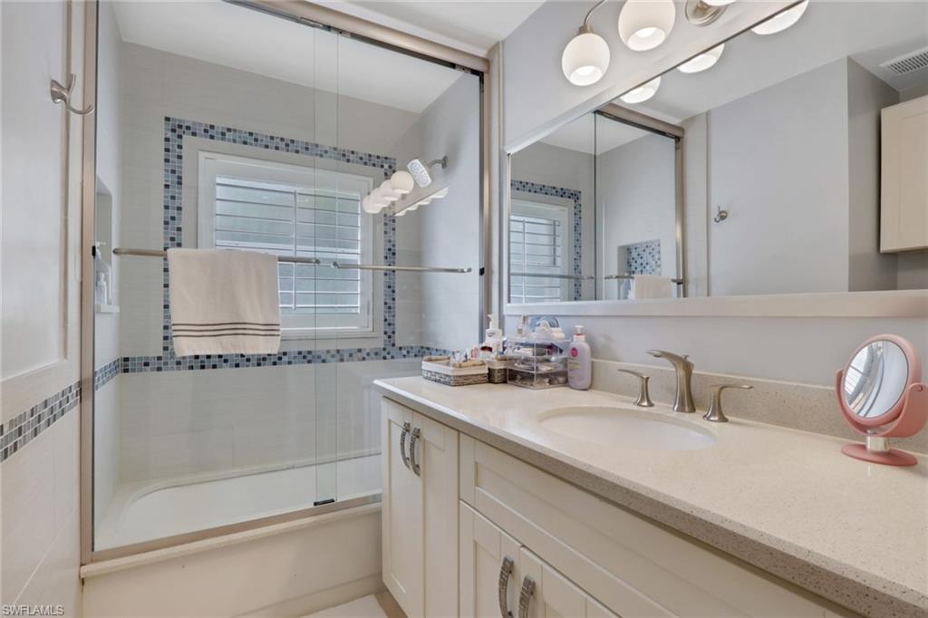 Bathroom with vanity and combined bath / shower with glass door