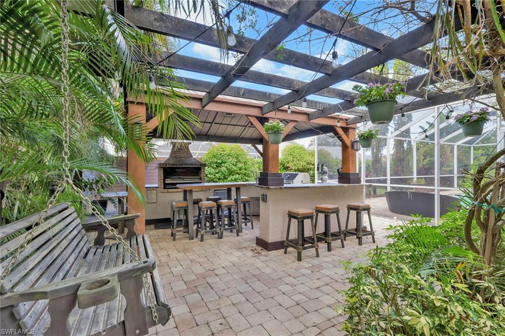 View of patio with a lanai, a sunroom, and an outdoor kitchen
