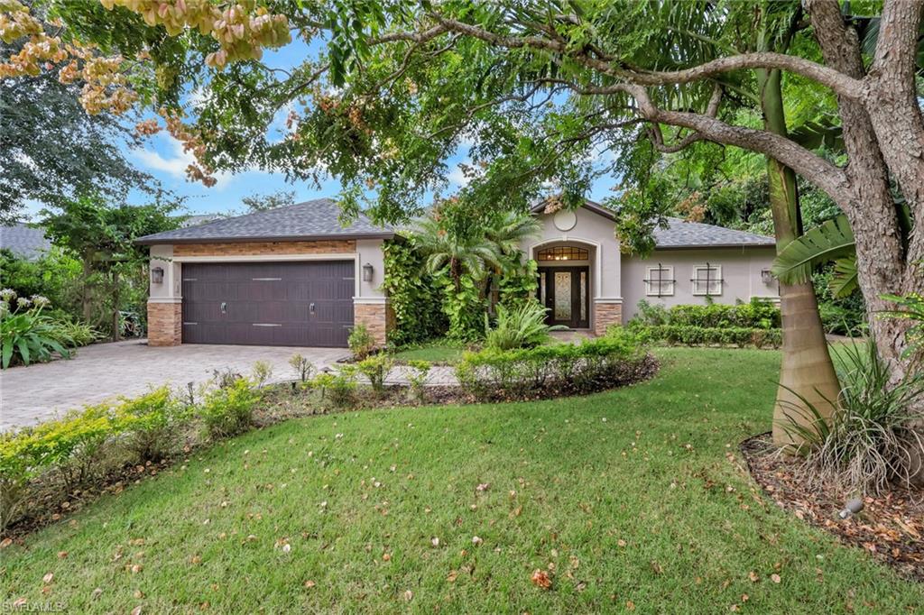 Ranch-style home with a front yard, roof with shingles, stucco siding, decorative driveway, and stone siding