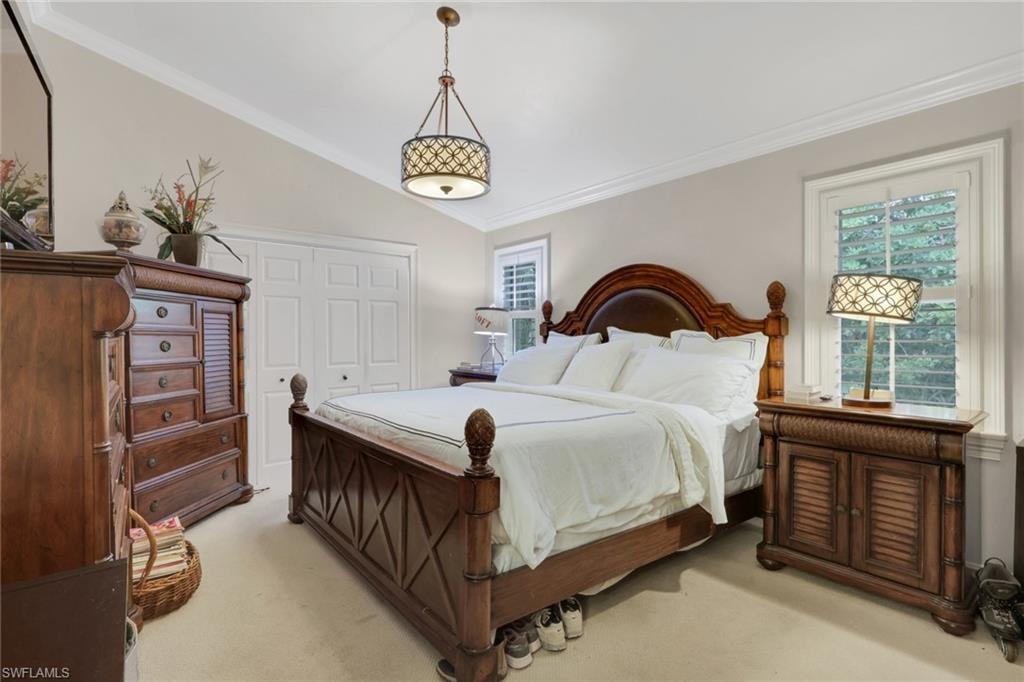 Bedroom featuring ornamental molding, lofted ceiling, a closet, and carpet