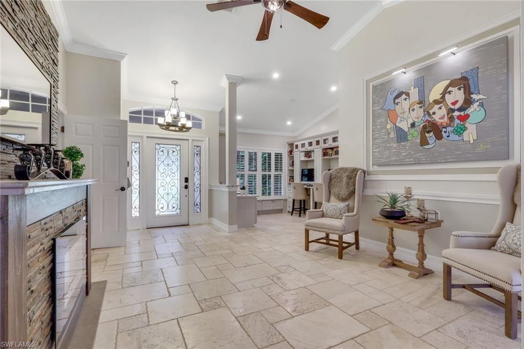 Entrance foyer with ornamental molding, stone tile floors, a chandelier, recessed lighting, and ornate columns