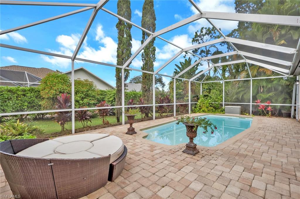 Outdoor pool with glass enclosure, a sunroom, and a patio