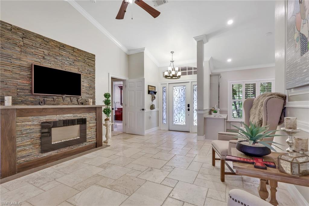 Foyer featuring ornamental molding, stone tile floors, a chandelier, a towering ceiling, and ceiling fan