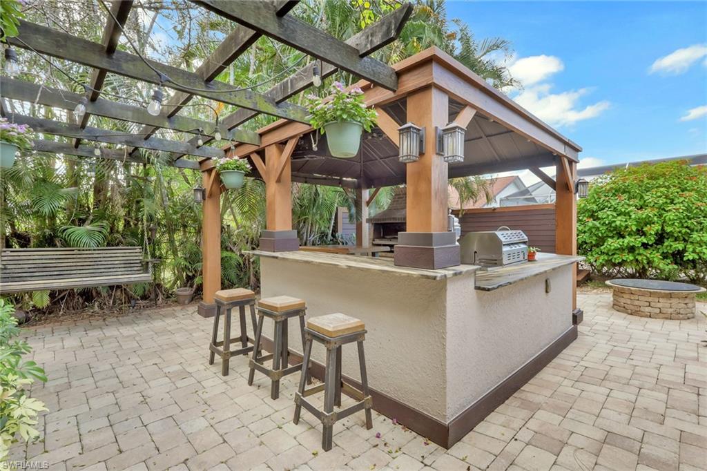 View of patio featuring area for grilling, an outdoor fire pit, and a gazebo