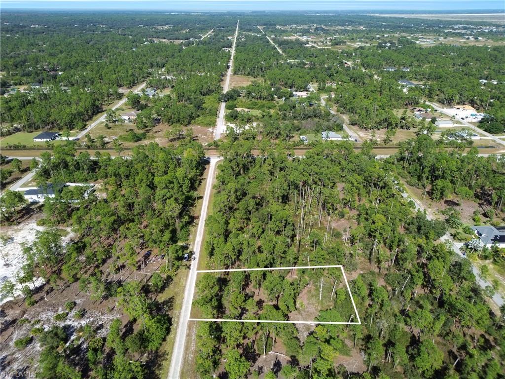 Aerial view of property and surrounding area featuring property boundaries highlighted and a forest