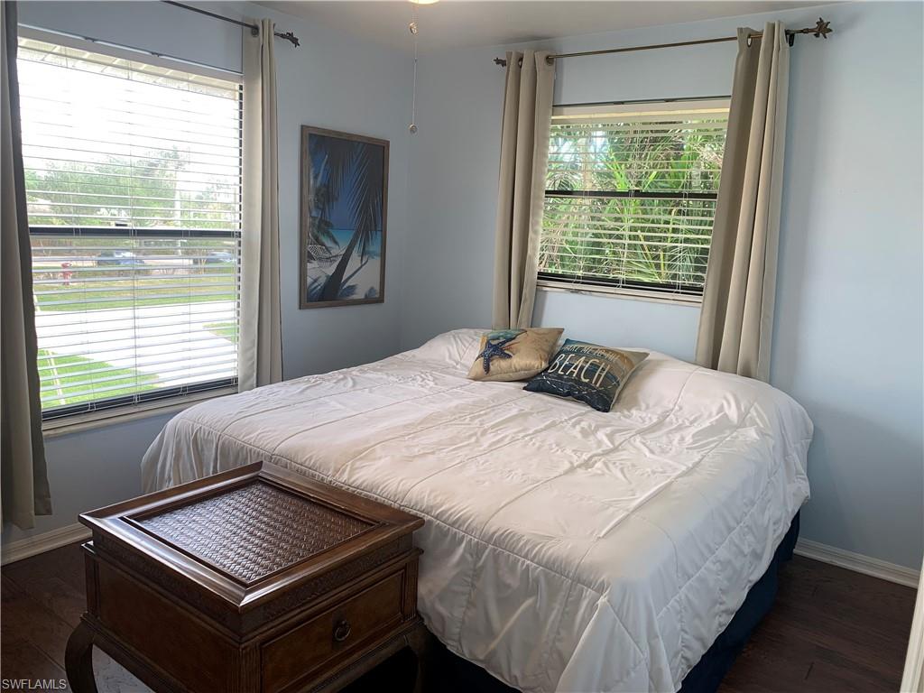 Bedroom with multiple windows and dark hardwood / wood-style floors