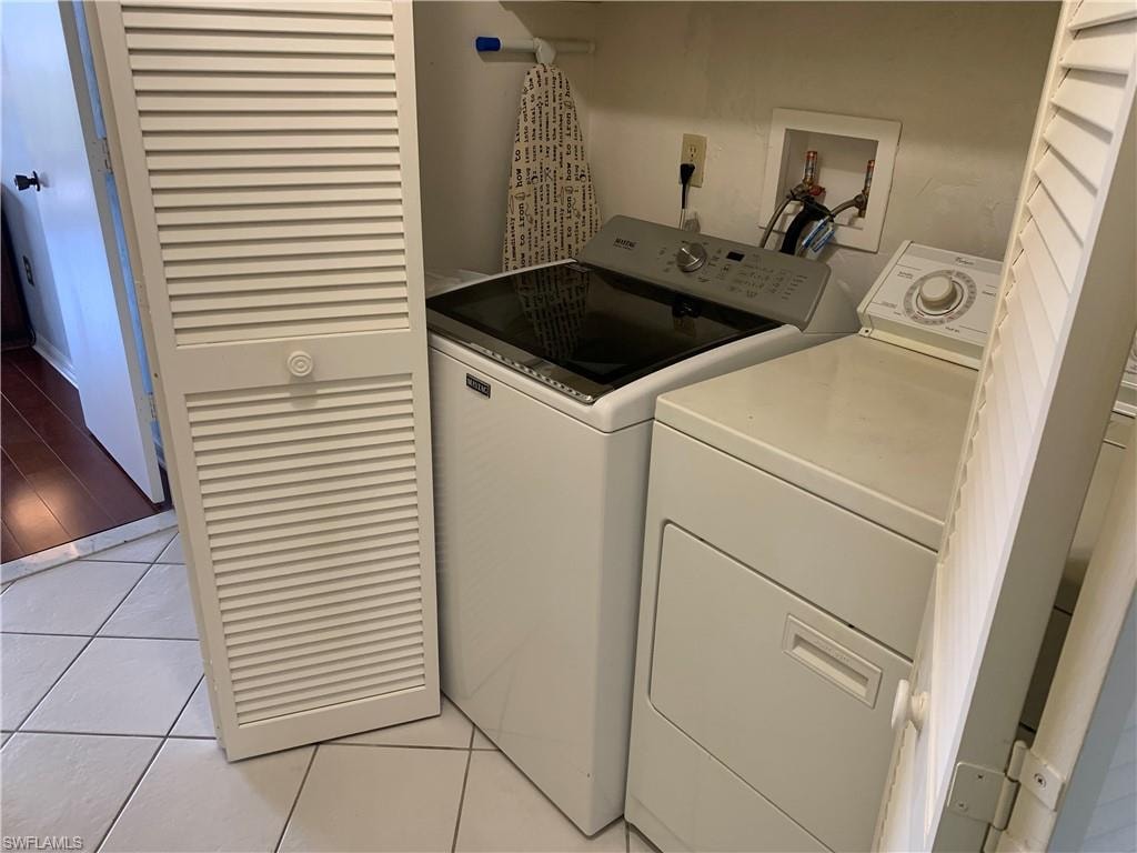 Laundry area with washer and clothes dryer and light tile patterned flooring