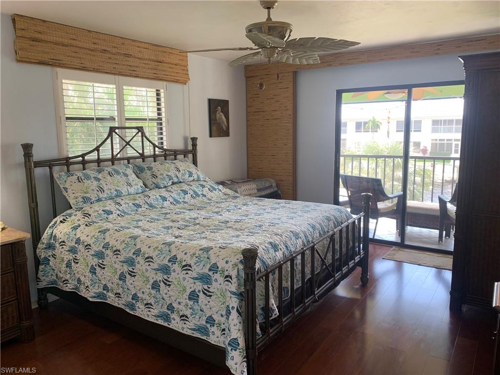 Bedroom featuring access to outside, multiple windows, ceiling fan, and dark hardwood / wood-style floors