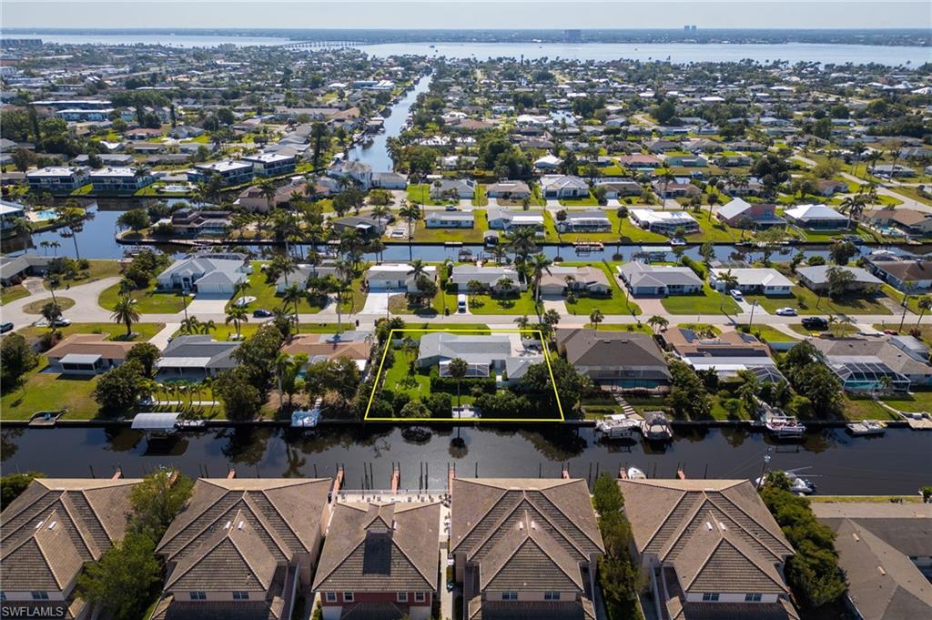 Aerial view of residential area with property boundaries highlighted and a nearby body of water