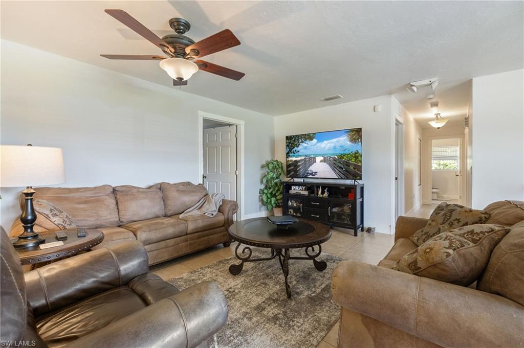 Living room with light tile patterned floors and a ceiling fan