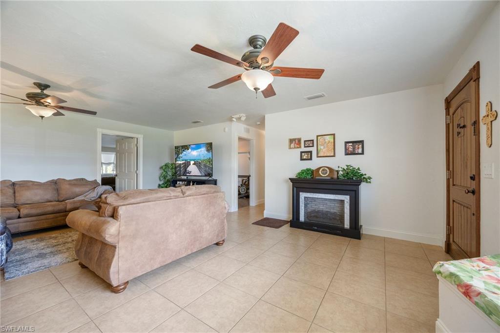 Living area featuring a fireplace, ceiling fan, and light tile patterned flooring